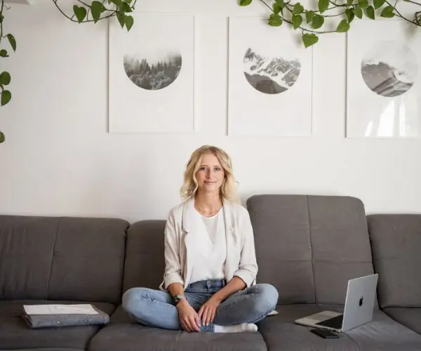 Katja Arndt, webdesignerin, sitzt auf Couch mit laptop und schaut in die Kamera